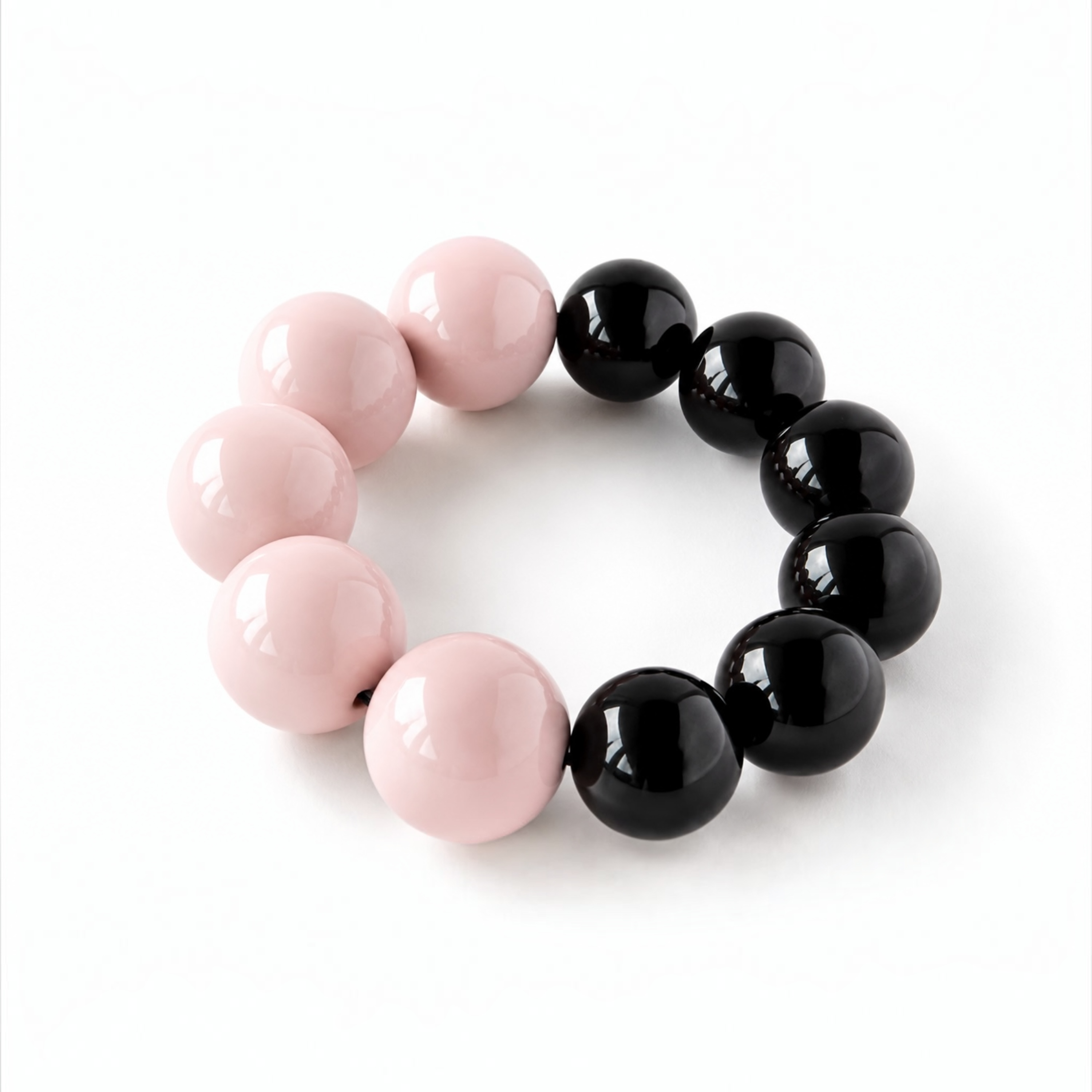 A beaded stretch bracelet featuring alternating glossy light pink and black round beads, displayed on a clean white background.