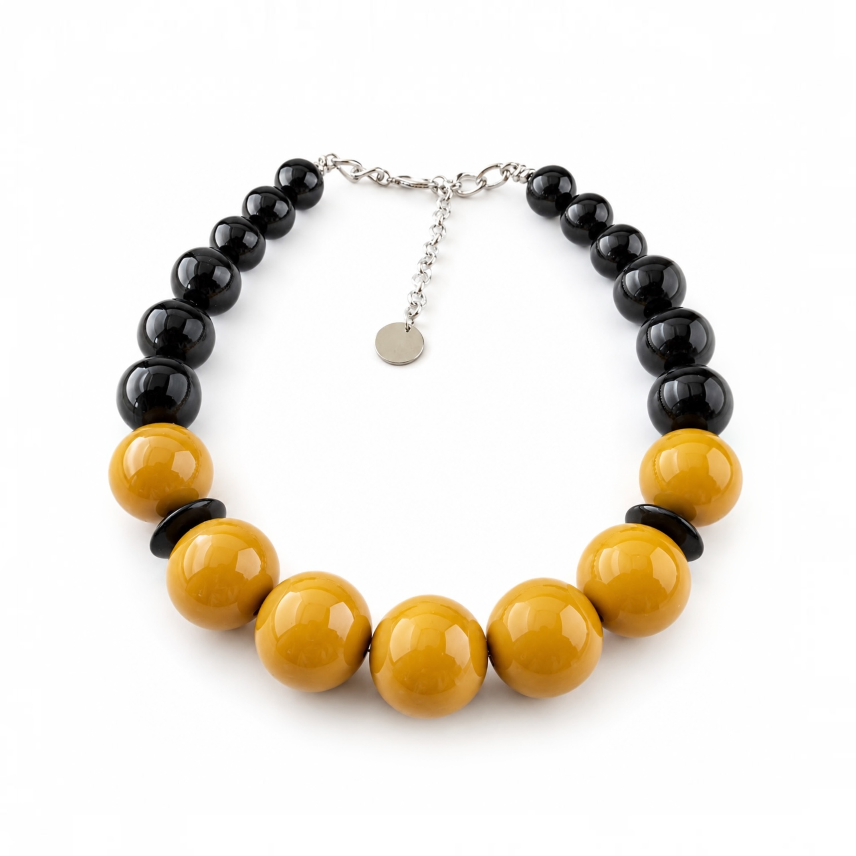 A beaded necklace featuring alternating glossy black round beads and large mustard-yellow round beads, with a silver-tone chain extender and small round tag, shown on a plain white background.