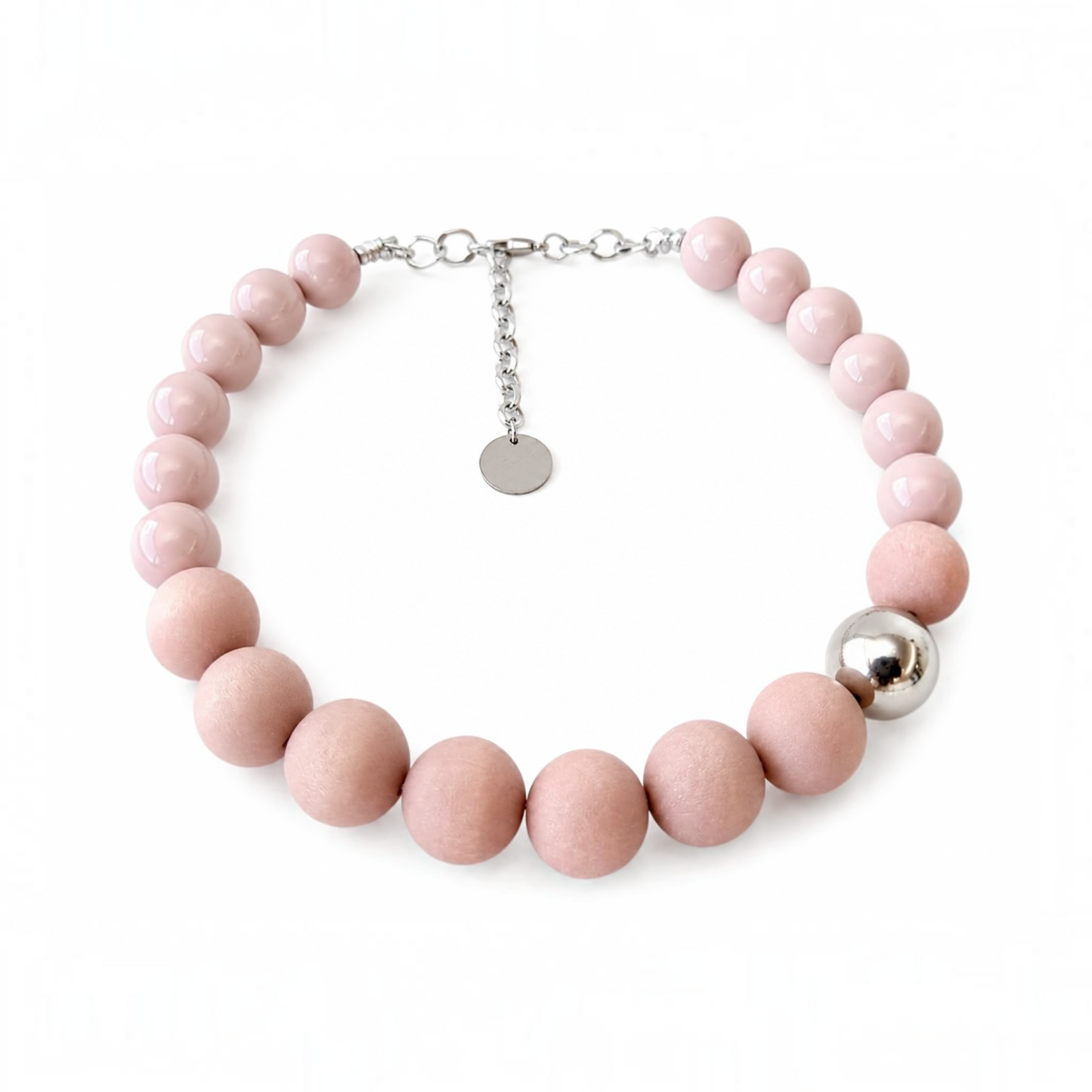 A beaded necklace made of matte light pink round beads, featuring a polished silver ball accent and a silver lobster clasp with an adjustable chain.